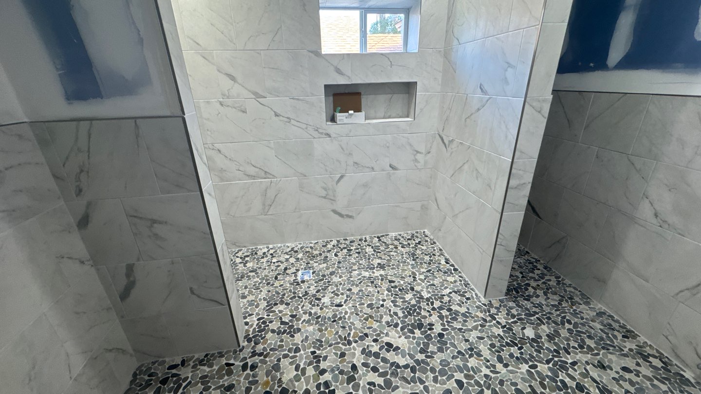 Tile shower with niche and pebble stone floor