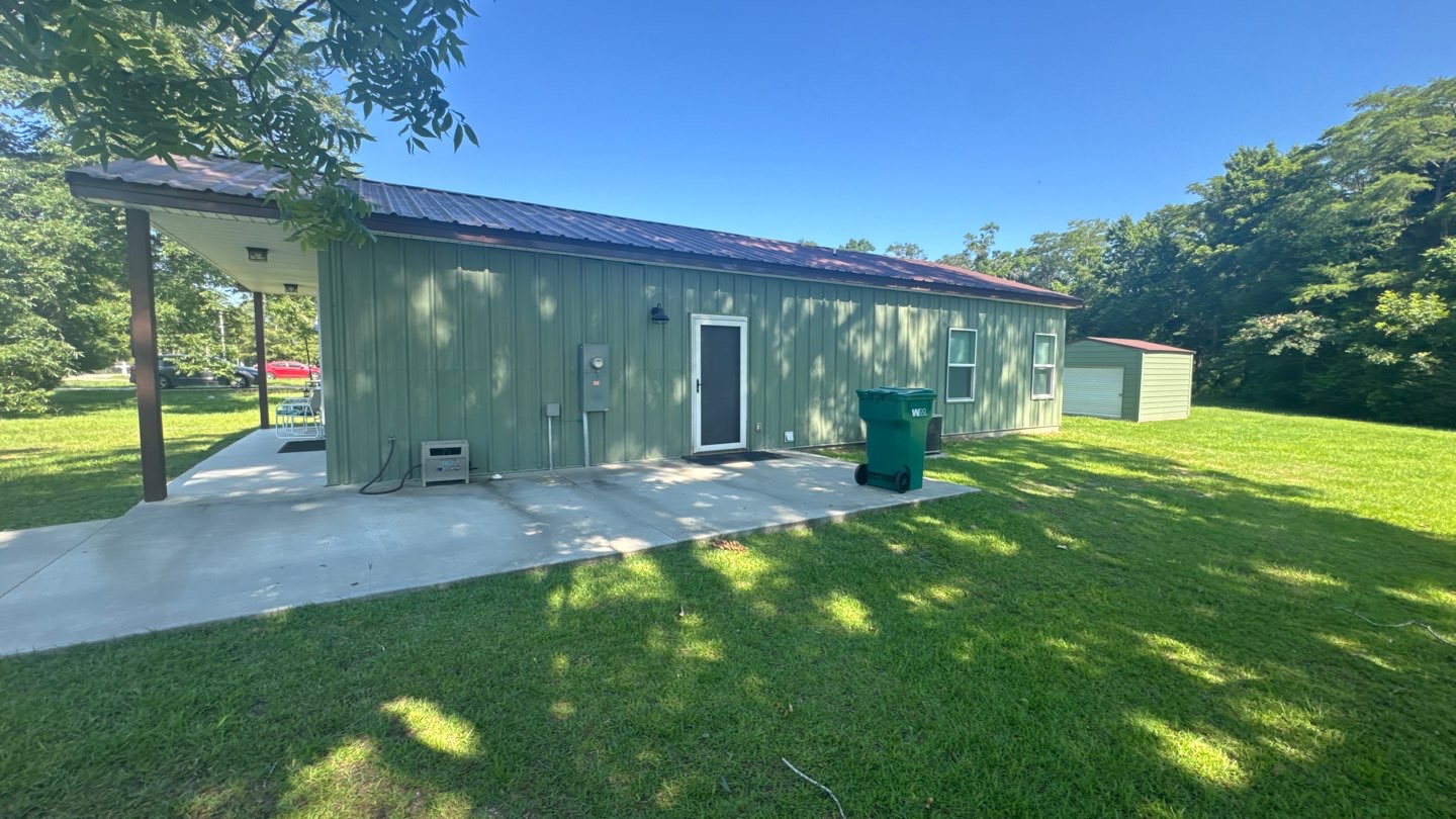 Second angle of the completed green metal building with covered porch slab in Northwest Florida
