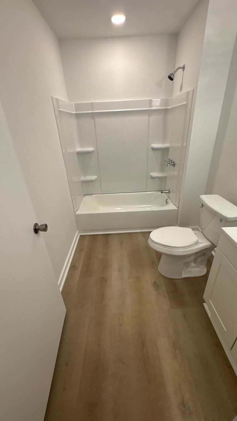 Bathtub, white surround and wood-look flooring