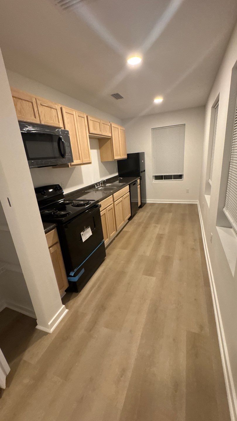 Completed galley kitchen with wood cabinets and black appliances